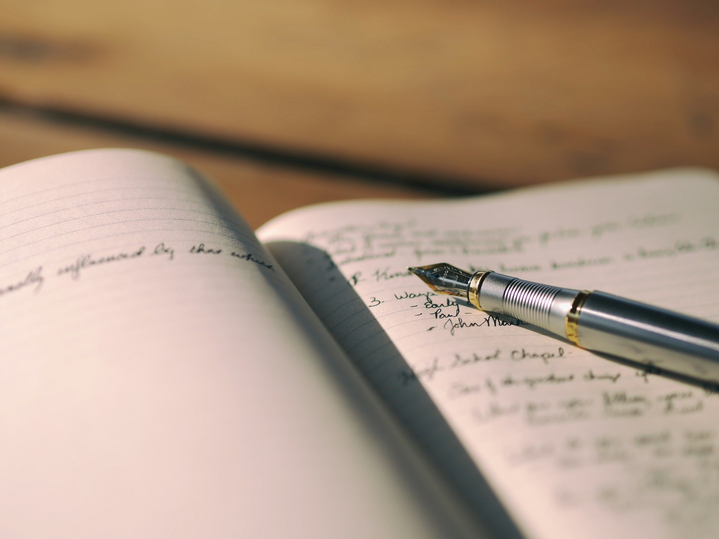 An open handwritten notebook with a fountain pen resting on the page
